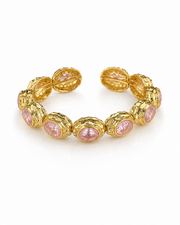 A gold cuff bracelet featuring textured oval links with round pink gemstone inlays, displayed on a clean white background.