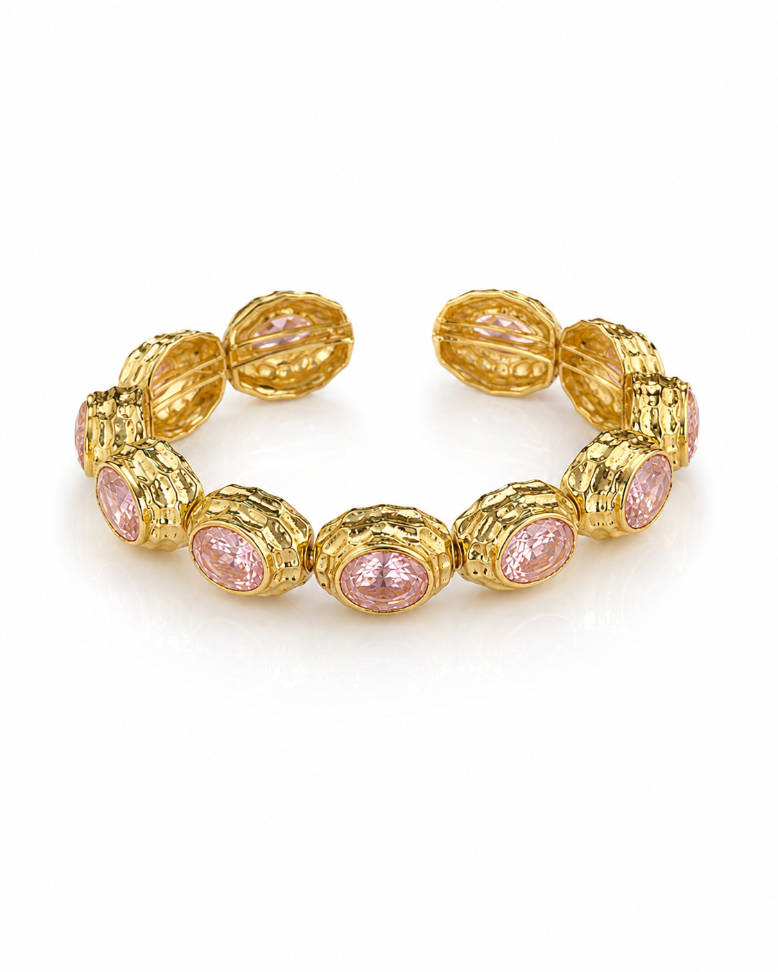 A gold cuff bracelet featuring textured oval links with round pink gemstone inlays, displayed on a clean white background.