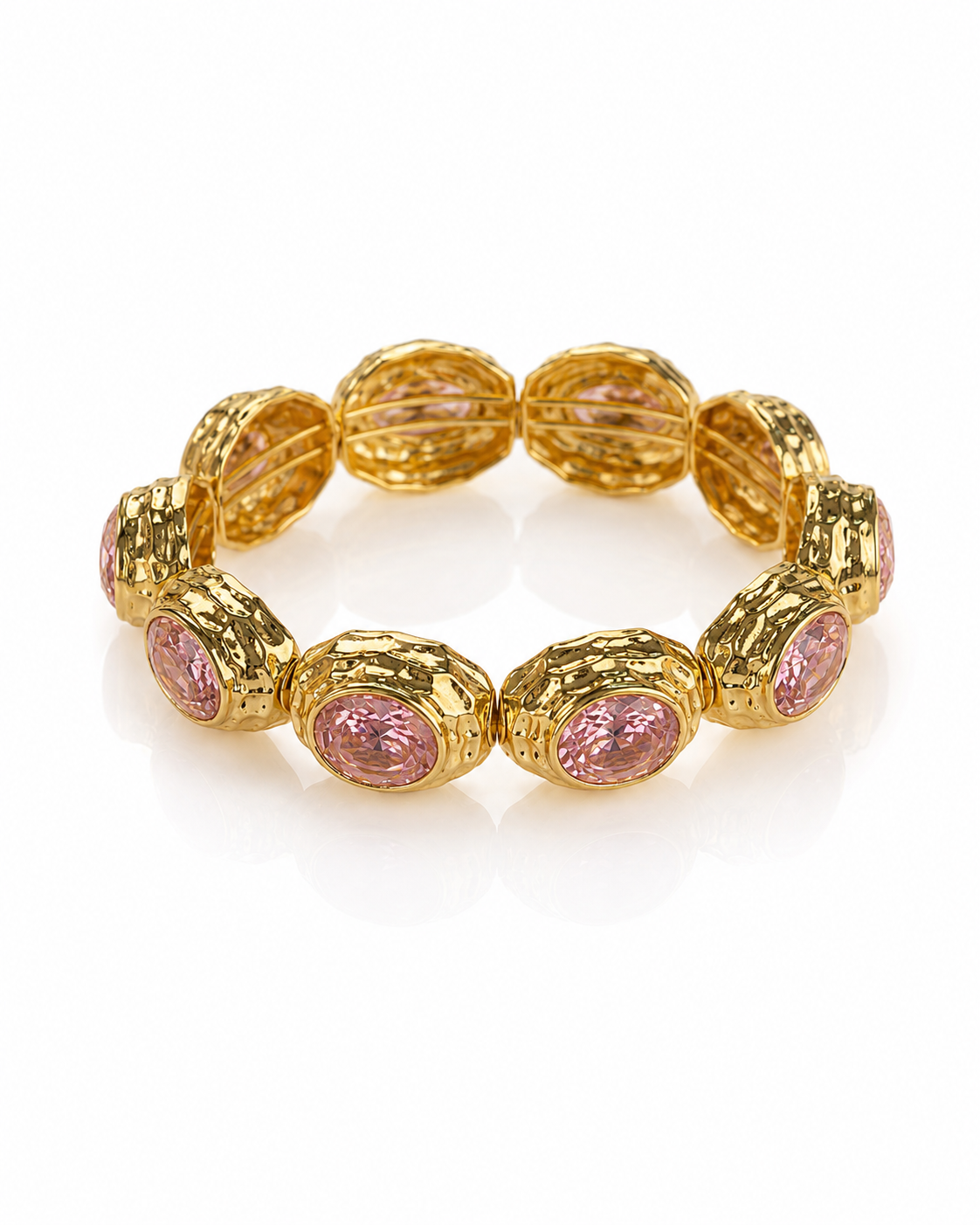 A gold stretch bracelet featuring textured oval links with round pink gemstone accents, displayed on a clean white background.