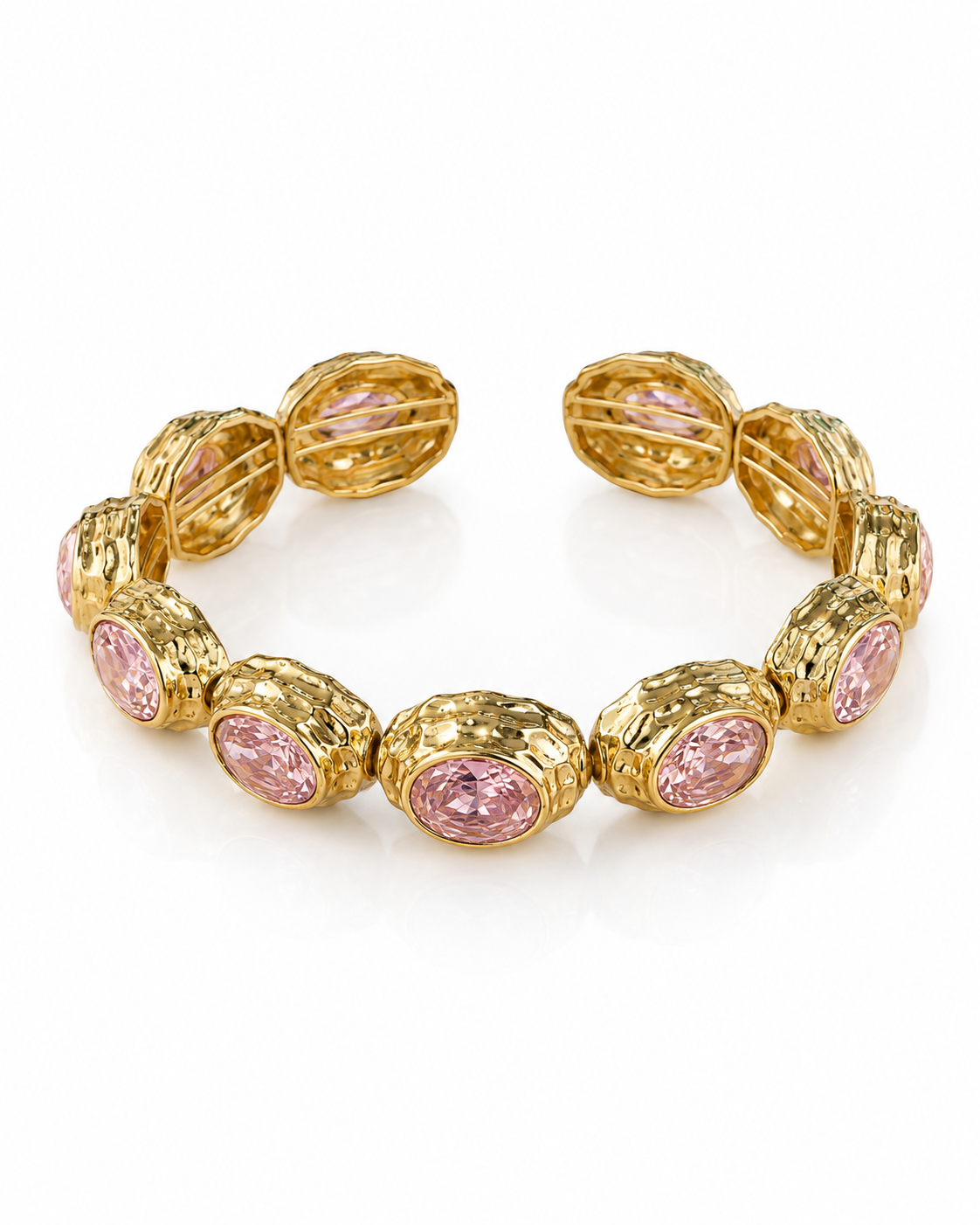 A gold cuff bracelet featuring oval pink gemstones in textured bezel settings, displayed on a clean white background.
