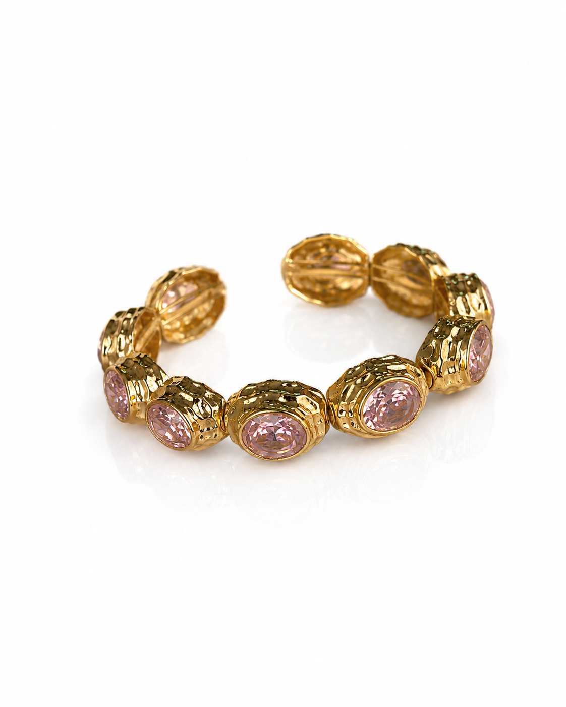 A gold-toned stretch bracelet featuring oval pink gemstones in textured bezel settings, displayed on a clean white background.